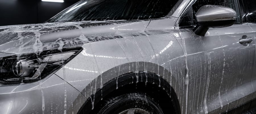 Foam sliding off a clean dark panel during a maintenance wash.