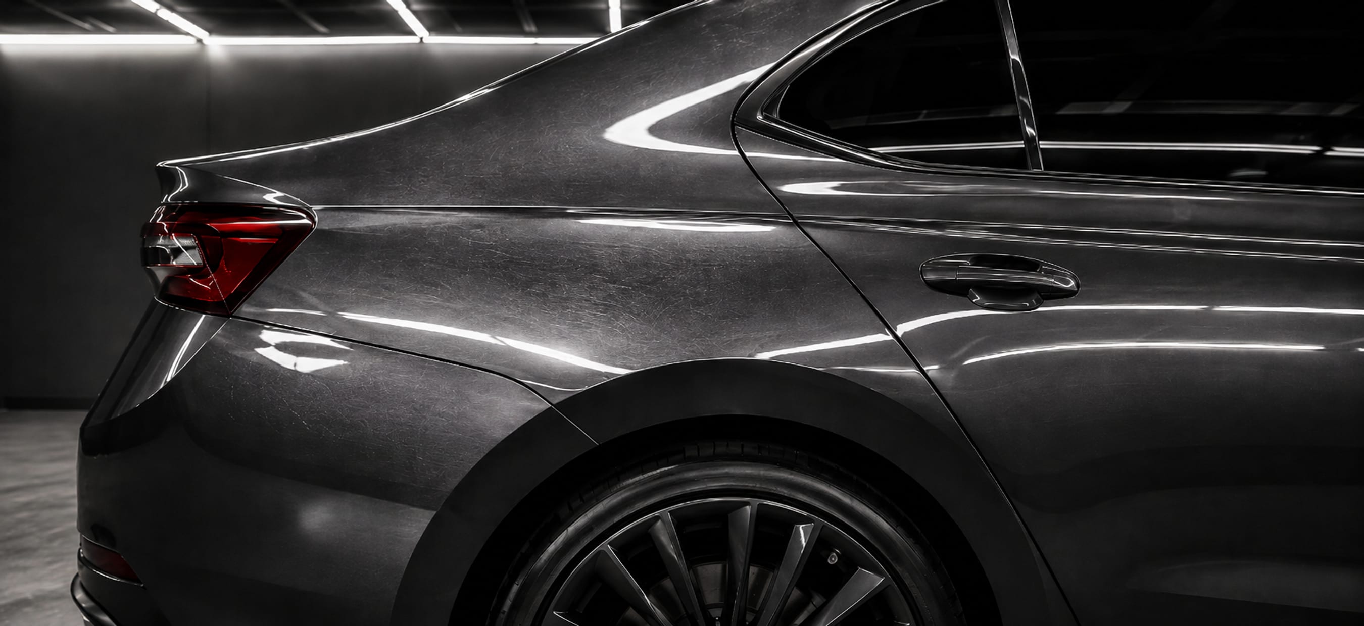 The same car panel before correction: a web of fine circular scratches breaking up the reflection.
